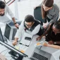 5 people in an office working in front of a computer referencing Scaling with dedicated development teams