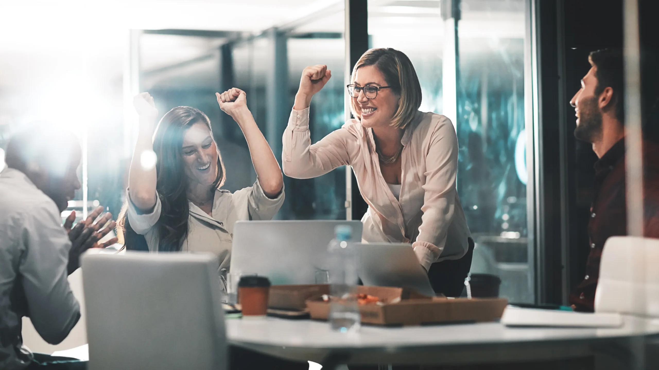 Group of people in an office celebrating in front of several computers