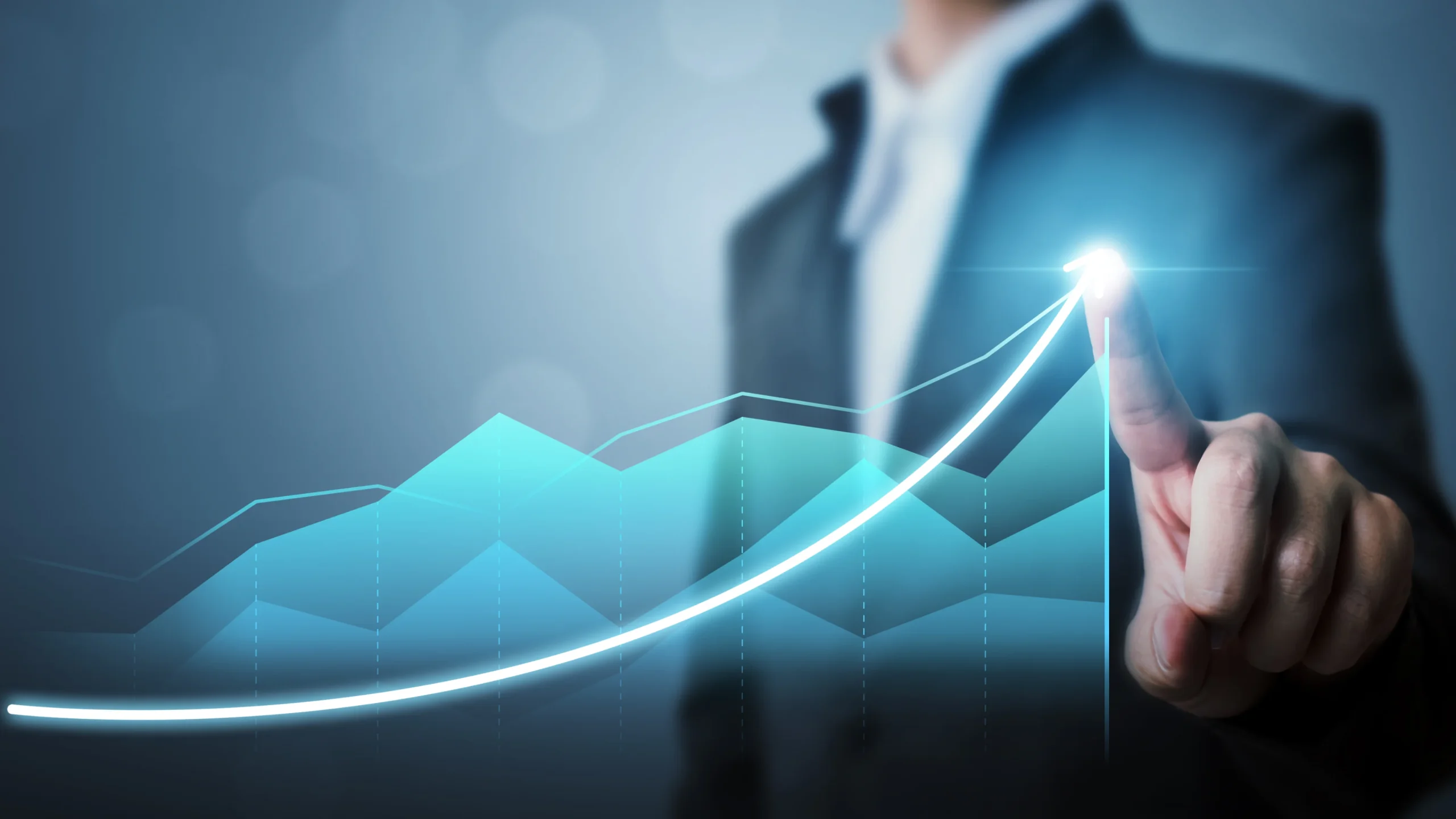Businessman in a suit pointing at a glowing upward-trending graph.