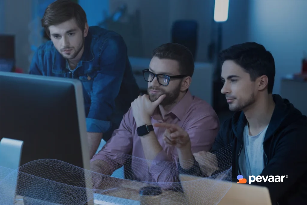Three IT professionals analyzing data on a computer screen, representing the key IT profiles that boost business technology in modern organizations.