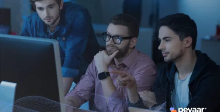 Three IT professionals analyzing data on a computer screen, representing the key IT profiles that boost business technology in modern organizations.