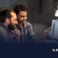 Two developers discussing a digital interface on a tablet and desktop, illustrating IT governance and strategy for startups in a tech workspace.