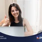 Smiling woman in front of her computer, representing the successful approval of a time off request through automation.