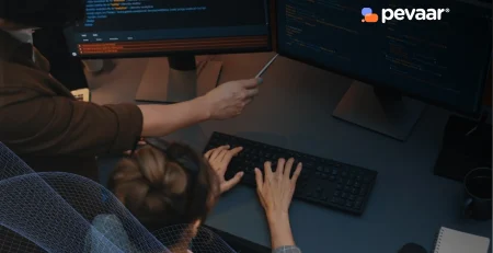 Two frontend and backend web developers collaborating on code, reviewing scripts on dual monitors in a modern workspace