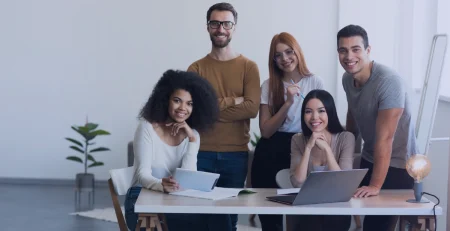 Partners working in front of a laptop enjoying the Power Apps project profitability app